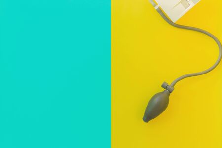 Flat lay: pear of blood pressure monitor, tonometer. Bright blue yellow background. Device for measurement of pulse, heart rate for people with hypertension, stress, problems, anxieties, worries.の写真素材