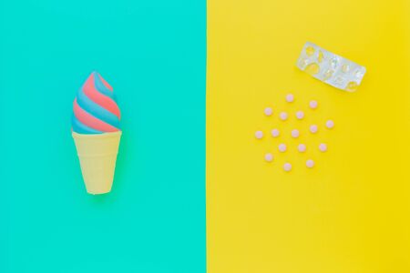 Flat lay antistress toy squish ice cream red, blue in waffle cone. Tablets, pills,blister. Bright blue yellow background.Compressing,soft,squeezable items to relieve stress,problems,anxieties,worries.の写真素材