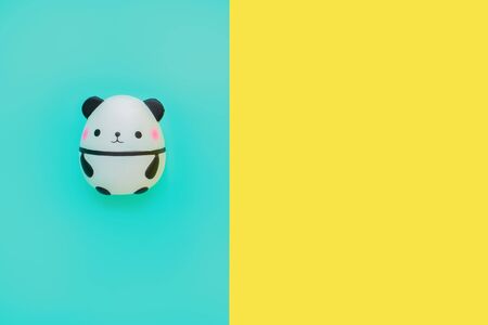 Flat lay antistress toy squish black white cute panda with pink cheeks.Bright yellow blue background.Compressing, soft, squeezable items to relieve stress, problems, anxieties, worries.Summer concept.の写真素材