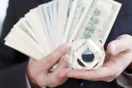 Businessman in suit, tie holds in hands drop of black oil of Brent brand in crystal cube.Pack of...