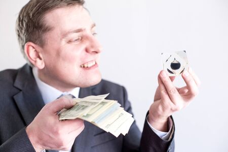 Nervous businessman in suit holds in hands drop of black oil of Brent brand and pack of dollars, screams,shouts.Crisis in financial market, falling and rising prices, quotes, changes in exchange rate.の写真素材