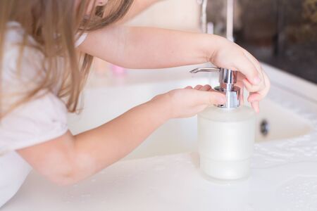 Little girls wash their hands in the sink with soap in the foam. Protection against coronovirus covid-2019 using personal hygiene and antibacterial gel.Mom takes care of health of children and family.の写真素材