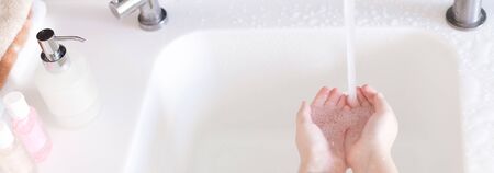 Little girls wash their hands in the sink with soap in the foam. Protection against coronovirus...