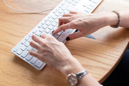Hands of business woman with black manicure typing on keyboard at home office. Distance learning.Hands,manicure. Wooden table,organizer.Remote work place.Quarantine of coronovirus pandemic covid-19.の写真素材