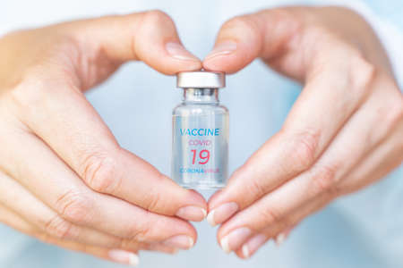 Vial with new vaccine for covid-19 coronavirus, flu, infectious diseases. Hands of doctor, nurse. Injection after clinical trials for vaccination of human, child, adult, senior. Medicine, drug concept.の写真素材