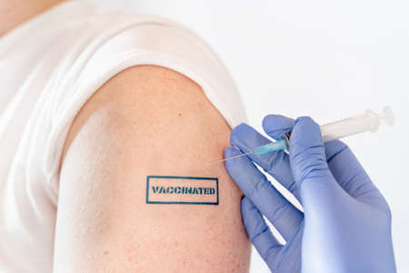 Patient hand with blue stamp vaccinated. Doctor's syringe with vaccine for covid-19 coronavirus,...