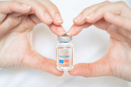 Vial with new usa, american vaccine for covid-19 coronavirus, flu, infectious diseases. Hand of doctor, nurse. Injection after clinical trials for vaccination of human, people. Medicine, drug concept.の写真素材