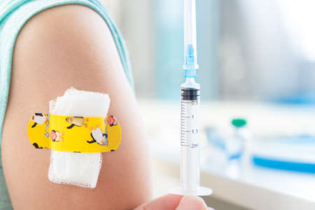 Vaccination of little girl in doctor's office. Kids funny adhesive plaster, gauze napkin Syringe...