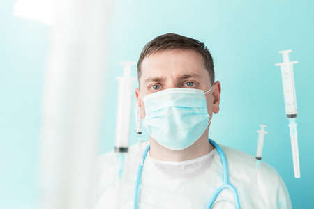 Doctor in blue face mask catches flying syringes. Thinking about vaccine for covid-19 coronavirus, flu, infectious diseases.Mass vaccination of people, population.Clinical trials for volunteers, human.の写真素材