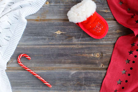New year flatl ay Christmas decorations Santa Claus mitten, caramel candy cane, white woolen plaid and red tablecloth with stars on a rustic wooden backgroundの写真素材