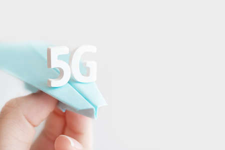 Flying paper plane with large white letters 5 G on gray background. Creative concept. Modern...