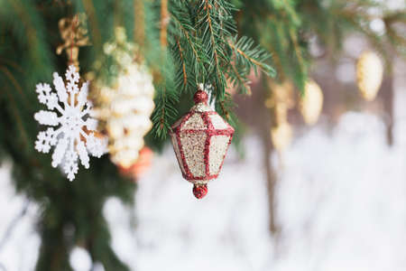 Christmas tree decoration, sparkling gold toy cone, snowflake, ball. Spruce, fir green branch in winter park covered with snow. New Year holiday atmosphere, spirit. Celebration in 2021.の写真素材