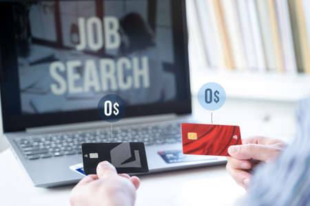 Zero balance, empty credit cards in hands. Remote job search in laptop. No money, unemployment, crisis, job loss. Looking for work at home. Hiring employees, freelancers for telework.の写真素材