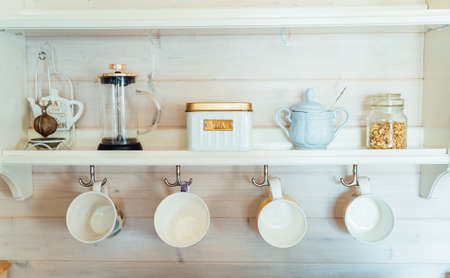 Kitchen wooden shelf with tea leaves in gold box and accessories, blue sugar bowl with spoon,...