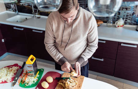 Cooking man, father, cooker. Preparation of soup, lunch, dinner in kitchen. Cutting vegetables,...