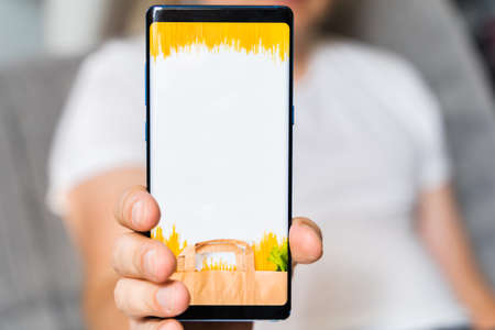 Hand with mobile phone. Online internet shopping, order through mobile application. Laptop. Home delivery of food, groceries from grocery store. Paper bag with pasta on screen. Payment by credit card.の写真素材