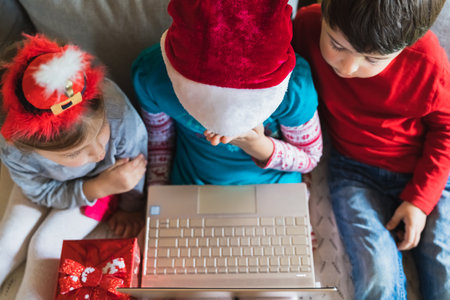 Little kids girls, boy have video call, onine virtual conference in laptop.Red Christmas santa claus,elf hat.の写真素材