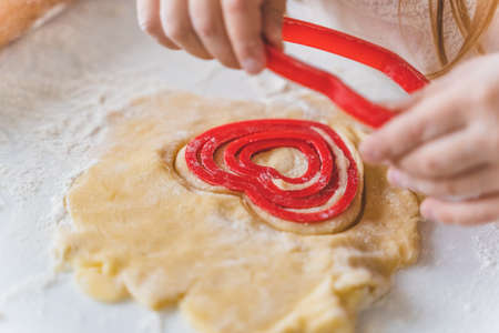 Little girls, sisters cooking homemade heart shaped cookies for valentine's day. Holiday for all...