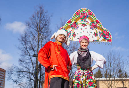 Jesters, buffoons on stilts in national costumes. Hat with earflaps,shirt,kokoshnik.Russian national...