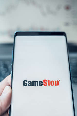 Russia Moscow 02.02.21 Mobile phone with logo of Gamestop in hand. Company making video games. Playing on trading exchange,price,market manipulation. Scandal with Reddit, Robinhood. Losses, crisis.のeditorial素材
