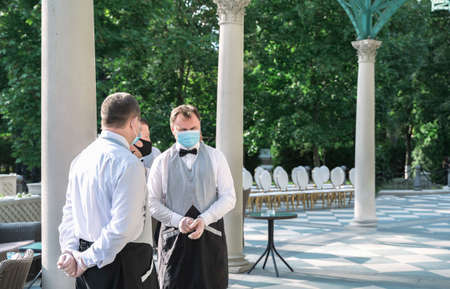 Russia Moscow 12.09.2020 Waiters in masks,gloves,vests serving wedding patry,holiday.Protective measures at events in restaurants,cafes.Hygiene,safety of stuff,guests.Coronavirus,covid-19.New reality.のeditorial素材
