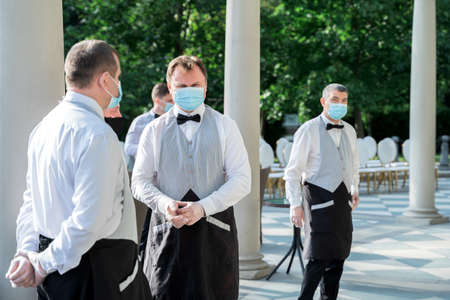 Russia Moscow 12.09.2020 Waiters in masks,gloves,vests serving wedding patry,holiday.Protective measures at events in restaurants,cafes.Hygiene,safety of stuff,guests.Coronavirus,covid-19.New reality.のeditorial素材