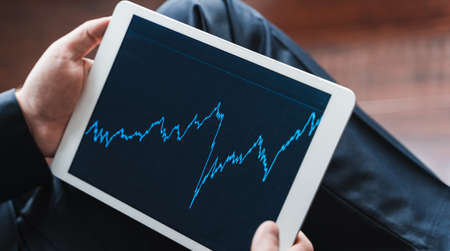 Businessman, investor,trader analyzing,looking at chart of stock prices in tablet. CEO,general manager.Bank investment.Finance company,hedge fund.Japanese candlestick,diagram.の写真素材