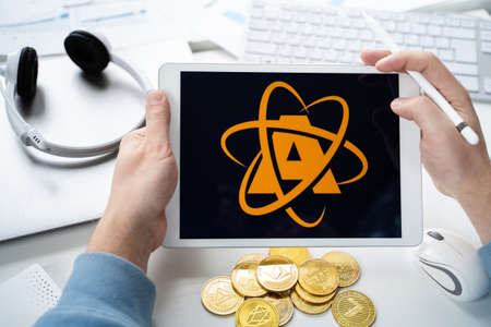Russia Moscow 05.05.2021.Man holding tablet with logo of NFT marketplace Atomic market. Non fungible...