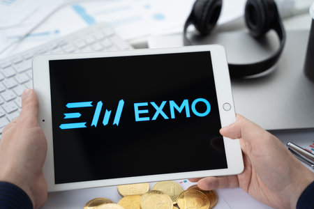 Russia Moscow 05.05.2021 Businessman holding tablet with logo of cryptocurrency stock exchange Exmo. Buy, sell, change crypto coins, diital money BTC, Bitcoin, ETH, Ethereum.Trading, investing to tokens.のeditorial素材