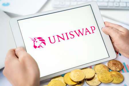 Russia Moscow 05/06/2021.Businessman with tablet.Logo of cryptocurrency stock exchange Uniswap.Trading blockchain platform to buy, sell digital crypto coins, tokens Bitcoin, Ethereum.Business, investing.のeditorial素材
