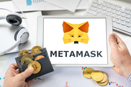 Russia Moscow 06.05.2021 Businessman, tablet. Logo of software cryptocurrency wallet, gateway Metamask. Blockchain application to buy, store, send, swap crypto coins, digital tokens. Bitcoin, Ethereum.のeditorial素材
