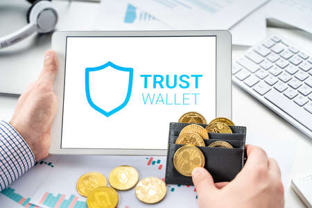 Russia Moscow 06.05.2021 Businessman, tablet. Logo of software cryptocurrency wallet, gateway Trust Wallet. Blockchain application to buy, store, send, swap crypto coins, digital tokens. Bitcoin, Ethereum.のeditorial素材