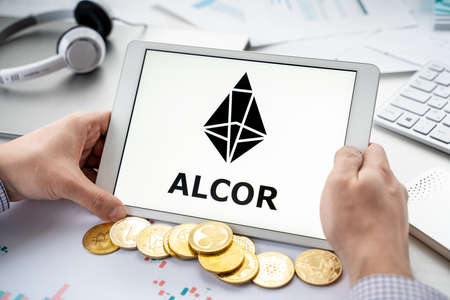 Russia Moscow 05/06/2021 Businessman with tablet.Logo of cryptocurrency stock exchange Alcor.Trading blockchain platform to buy, sell digital crypto coins, tokens Bitcoin, Ethereum.Business, investing.のeditorial素材