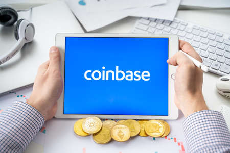 Russia Moscow 05/06/2021.Businessman with tablet.Logo of cryptocurrency stock exchange Coinbase.Trading blockchain platform to buy, sell digital crypto coins, tokens Bitcoin, Ethereum.Business, investing.のeditorial素材