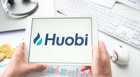 Russia Moscow 05/06/2021 Businessman with tablet.Logo of cryptocurrency stock exchange Huobi.Trading blockchain platform to buy, sell digital crypto coins Bitcoin, Ethereum.Business, investing to tokens.のeditorial素材