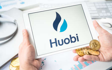Russia Moscow 05/06/2021 Businessman with tablet.Logo of cryptocurrency stock exchange Huobi.Trading blockchain platform to buy, sell digital crypto coins Bitcoin, Ethereum.Business, investing to tokens.のeditorial素材