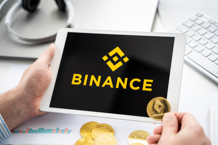 Russia Moscow 06.05.2021.Businessman with tablet.Logo of cryptocurrency stock exchange Binance.Trading blockchain platform to buy,sell digital crypto coins,tokens Bitcoin,Ethereum.Business,investing.のeditorial素材