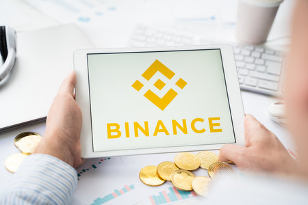 Russia Moscow 06.05.2021.Businessman with tablet.Logo of cryptocurrency stock exchange Binance.Trading blockchain platform to buy,sell digital crypto coins,tokens Bitcoin,Ethereum.Business,investing.のeditorial素材