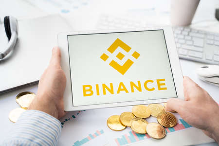Russia Moscow 05/06/2021 Businessman with tablet.Logo of cryptocurrency stock exchange Binance.Trading blockchain platform to buy, sell digital crypto coins, tokens Bitcoin, Ethereum.Business, investing.のeditorial素材