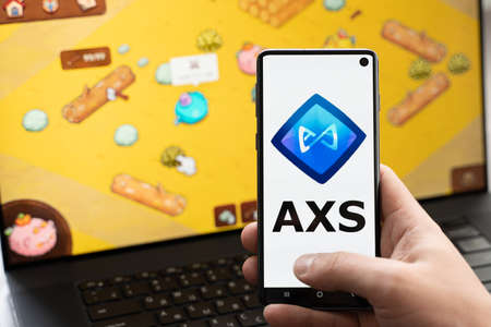 Russia Moscow 30.05.2021.Logo,screenshot of blockchain nft ethereum cryptocurrency game Axie in laptop,mobile phone.Man playing,collecting,creating crypto pet,heroes. Earning digital money tokens AXS.のeditorial素材