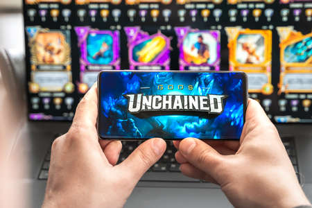 Russia Moscow 30.05.2021.Logo, screenshot of blockchain nft ethereum cryptocurrency game Unchained gods in laptop.mobile phone. Man playing,collecting cards,crypto coins. Digital money. Lands,heroes.のeditorial素材