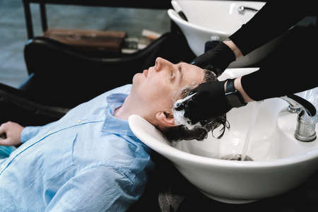 Visit to the barbershop. Young stylish man, businessman makes fashionable haircut. Barber,...