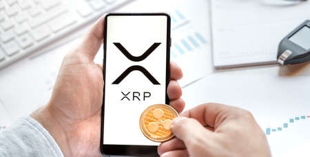 Russia Moscow 24.06.21 Logo of Ripple coin in mobile phone. Cryptocurrency XRP token. Trading...