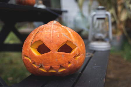 Orange pumpkin for halloween in black witch, wizard hat, jack-o-lantern with scary carved eyes, mouth.Candles on wooden table near barn. DIY home,street decoration, entertainment for children, horror.の写真素材