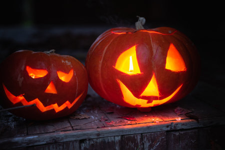 Jack-o-lantern hand made from big pumpkins with candle lights in eyes,nose,mouth. Celebratiion of halloween holiday.Cut with knife,take out pulp with seeds.Outdoors activity,backyard.Children's party.の写真素材