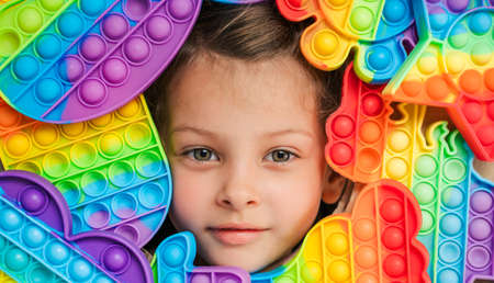 Little girl,kid,child head among many, lots of colorful. Children play. Trendy silicone anti stress colorful sensory push toy . Flapping fidget. Rainbow color.Cure of autism.Stress reliever.の写真素材