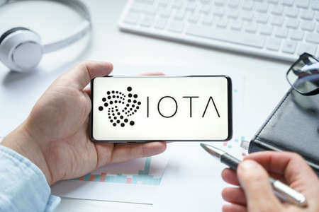 Russia, Moscow 08.06.2021.Logo of IOTA blockchain protocol in mobile phone.Distributed Ledger Technology. Facilitate microtransactions between devices on Internet of Things.Consensus algorithm Tangle.のeditorial素材