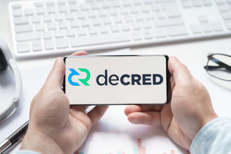Russia Moscow 08.06.2021 Logo of Decred coin in mobile phone. Autonomous digital cryptocurrency token. Trading blockchain platform to buy,sell on decentralized exchange DEX. Digital money.Business.のeditorial素材