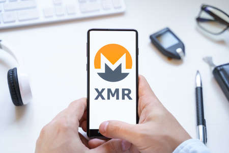 Russia Moscow 12.06.2021 Logo of Monero coin in mobile phone. Cryptocurrency XMR token. Trading blockchain platform to buy,sell on decentralized exchange DEX. Digital money.Business,investing.のeditorial素材