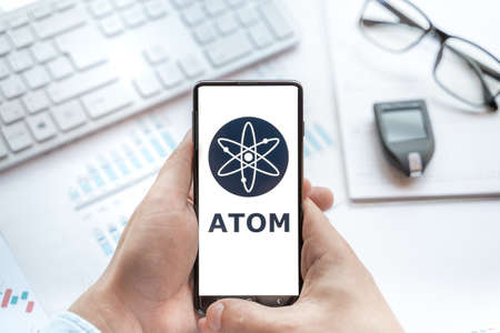 Logo of Atom coin in tablet. Cryptocurrency Cosmos token. Trading blockchain platform to buy,sell on decentralized exchange DEX,DEFI. Digital money.Business,investing.のeditorial素材